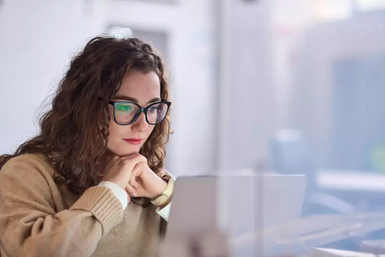 Symboldbild Praktikum – Frau mit Brille liest am Laptop